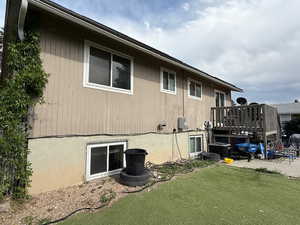 View of side of home with a deck, central AC unit, and a lawn