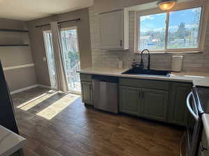 Kitchen with appliances with stainless steel finishes, a sink, decorative backsplash, and dark wood-type flooring