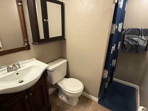 Bathroom with toilet, vanity, tile patterned floors, and baseboards