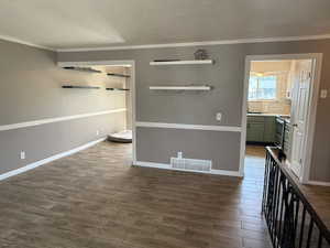Unfurnished room with ornamental molding, dark wood-type flooring, and baseboards