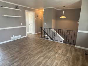 Unfurnished room with wood finished floors, ornamental molding, and baseboards