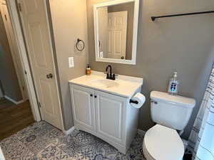 Bathroom with vanity, toilet, baseboards, and tile patterned floors