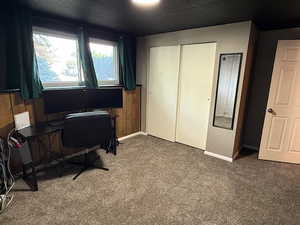 Carpeted home office featuring baseboards and wooden walls