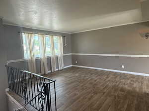 Unfurnished room with wood finished floors, crown molding, and baseboards