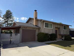 View of front of house featuring a garage, driveway, a chimney, stucco siding, and brick siding