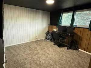 Office space with carpet flooring, wood walls, and baseboards