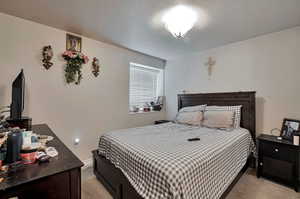 Bedroom featuring light colored carpet, a textured ceiling, and baseboards