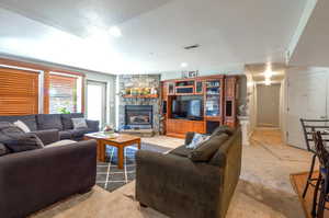 Living room featuring light colored carpet, a fireplace, and a textured ceiling