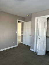 upstairs bedroom featuring dark carpet, a closet, and a textured ceiling