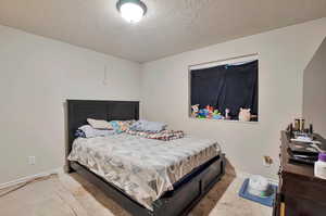 Carpeted bedroom featuring a textured ceiling and baseboards