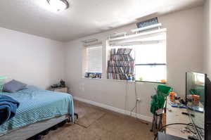 Carpeted bedroom with a textured ceiling and baseboards