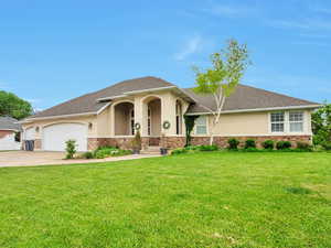 View of front of property featuring stucco siding, stone siding, concrete driveway, and an attached garage