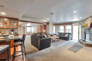 Living room featuring light colored carpet, a stone fireplace, recessed lighting, and a textured ceiling