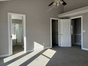 Primary bedroom with ensuite featuring vaulted ceiling, carpet flooring, and a ceiling fan