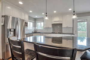 Kitchen featuring appliances with stainless steel finishes, custom range hood, a sink, white cabinets, and recessed lighting