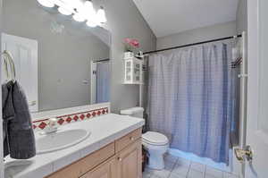 Bathroom with toilet, vanity, tile patterned floors, shower / tub combo with curtain, and backsplash