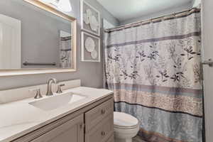 Full bath with vanity, toilet, and curtained shower