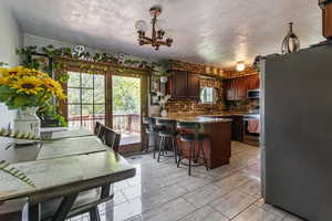 Kitchen featuring stainless steel appliances, a peninsula, plenty of natural light, a chandelier, and a textured ceiling