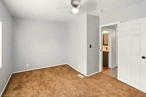 Unfurnished room featuring light carpet, ceiling fan, and baseboards