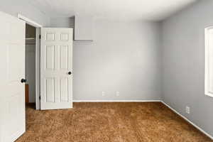 Unfurnished bedroom with carpet floors and baseboards