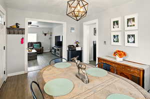 Dining room featuring baseboards, ceiling fan, a chandelier, and wood finished floors