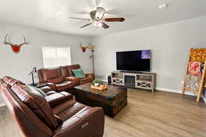 Living area with light wood finished floors, ceiling fan, and baseboards