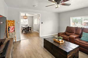 Living area featuring light wood-style floors, plenty of natural light, a ceiling fan, and baseboards
