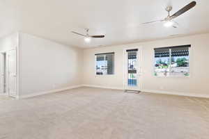 Empty room featuring ceiling fan, light carpet, and baseboards