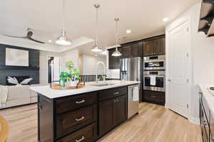 Kitchen featuring appliances with stainless steel finishes, a sink, light countertops, light wood-style flooring, and recessed lighting