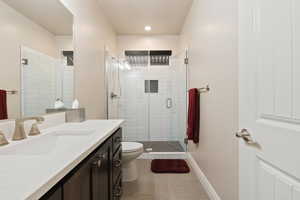Bathroom featuring toilet, tile patterned floors, vanity, a shower stall, and baseboards