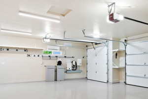 Garage with a garage door opener, baseboards, and a wall mounted AC