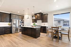 Kitchen with appliances with stainless steel finishes, light countertops, dark brown cabinets, light wood-type flooring, and recessed lighting