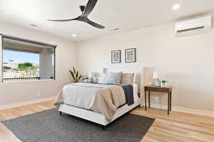 Bedroom with an AC wall unit, baseboards, wood finished floors, recessed lighting, and ceiling fan