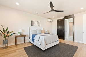 Bedroom featuring a wall mounted air conditioner, light wood finished floors, baseboards, recessed lighting, and a ceiling fan