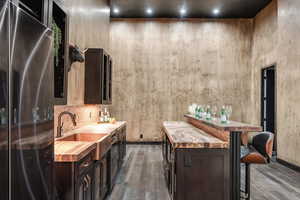 Bar with freestanding refrigerator, dark wood-style floors, a sink, and baseboards