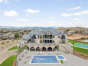 Back of house with a balcony, stone siding, a mountain view, and a patio area