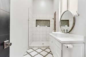 Bathroom featuring a stall shower, vanity, inlaid floor details, and baseboards