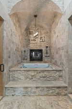 Unfurnished living room with a fireplace, vaulted ceiling, and tile walls
