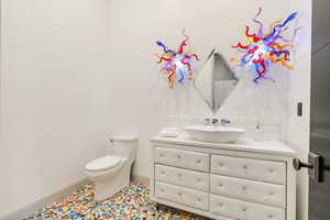 Half bath featuring toilet, baseboards, and vanity