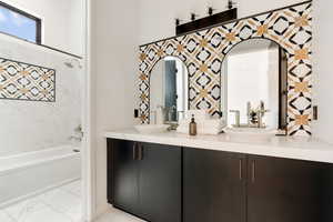 Bathroom featuring double vanity, shower / bath combination, and marble finish floors