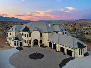 French provincial home with stone siding, curved driveway, a mountain view, an attached garage, and a high end roof