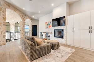 Living area with a tiled fireplace, light wood finished floors, and recessed lighting