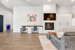 Living room with light wood finished floors, recessed lighting, baseboards, and a glass covered fireplace