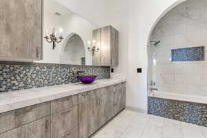 Full bathroom featuring vanity, tiled shower / bath, backsplash, and marble look tiles