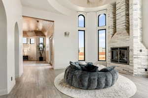 Living room with a large fireplace, arched walkways, light wood finished floors, baseboards, and vaulted ceiling