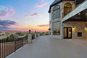 Patio terrace at dusk with a balcony, a patio area, and french doors
