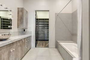Full bathroom with vanity, a walk in closet, tile patterned flooring, and tiled shower / bath combo