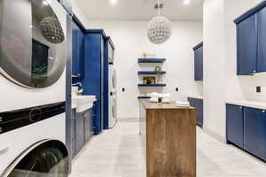 Washroom with stacked washer and clothes dryer, cabinet space, a chandelier, and recessed lighting