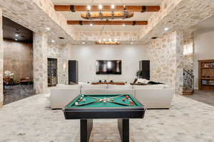 Playroom with a chandelier, beamed ceiling, a high ceiling, and pool table
