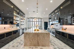 Kitchen featuring appliances with stainless steel finishes, dark cabinets, brick floors, tasteful backsplash, and a sink